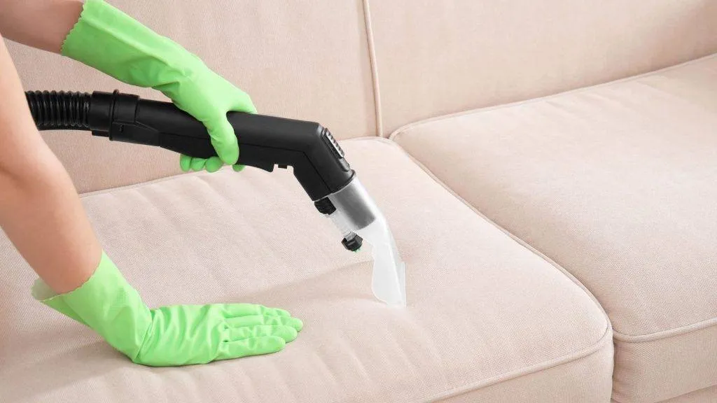 Cleaning upholstery with green gloves